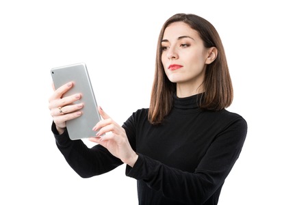 Woman business technology theme. Beautiful young caucasian woman in black shirt posing standing with tablet hands on white isolate background. Profession Marketer Sales Social Media Advertising.の写真素材