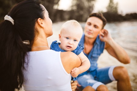 A young, beautiful family of three. Mom, Dad and daughter in the arms of my father play, rejoice,...
