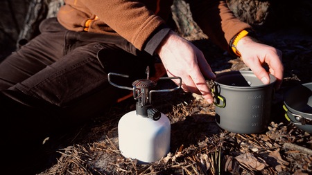 The theme of tourism is hiking and traveling in nature. Hands A Caucasian man uses equipping to cook...