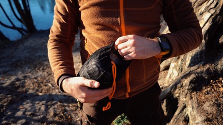 The theme of tourism is hiking and traveling in nature. Hands Caucasian man unpacking, setting the...