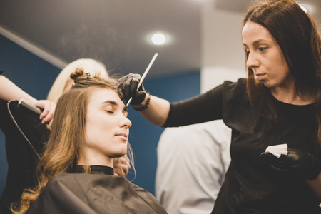 Professional Make Up Artist Doing Make Up In Beauty Salon. Eyebrow dyeing. master paints eyebrows with henna to beautiful girl, paints with brush in salon beautician makeup artist. Brow architecture.の写真素材