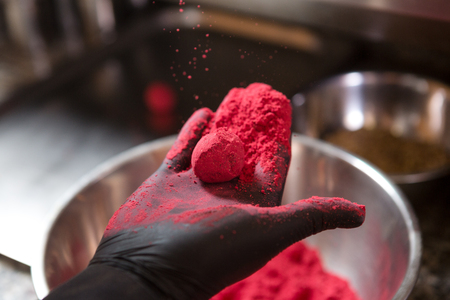 Theme cooking chocolates truffle. Close-up hand Young Caucasian woman and man cook with tattoo and in uniform prepares, makes round balltake the sweetness of cake. Confectioner covers raspberry puer.の写真素材