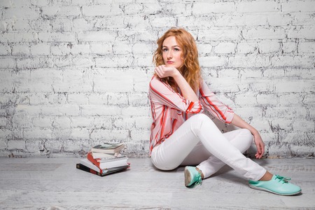 happy student girl with red hair and freckles prepares homework, prepares for homework sitting on...