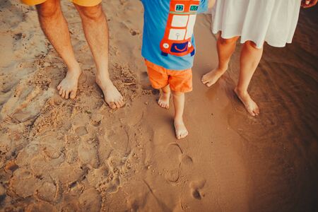 Happy family on the beach. Closeup of family feet with boy baby walking on sand. Man and woman holding their baby. Walk by the river. Travel lifestyle, parents with kids on summer vacation.の写真素材
