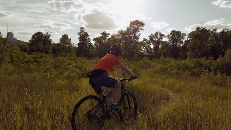 Young Athletic Caucasian woman Riding Mountain Bikes in the Beautiful Field of Feather Grass....