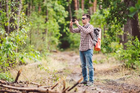 Man hiker taking photo smart phone in forest. Attractive Traveler Making Photo With Mobile Phone....