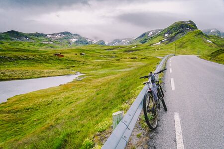 Bike with active equipment at norway mountains scene. Bicycle On Mountain. Bicycle Parked On road Against Mountains. Bicycle tourism in norwegian mountains, scandinavia and europe active life.の写真素材