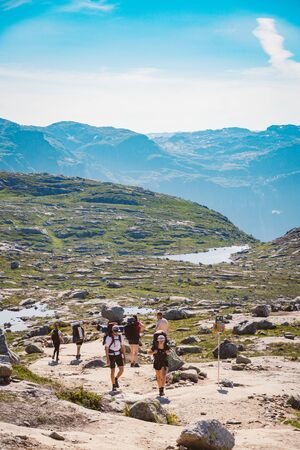 July 26, 2019. Norway tourist route on the trolltunga. People tourists go hiking in the mountains of Norway in fine sunny weather to thetrolltunga. Hiking backpack theme.のeditorial素材