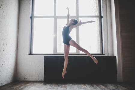 Plasticity slim woman dancing near window. Professional dancer enjoy dance. Lady Dancer Training Modern Ballet In Class. Contemporary dance performer. Daylight, silhouette beautiful body. Dance theme.の写真素材