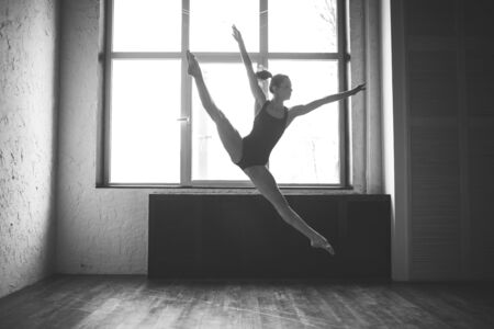 Plasticity slim woman dancing near window. Professional dancer enjoy dance. Lady Dancer Training Modern Ballet In Class. Contemporary dance performer. Daylight, silhouette beautiful body. Dance theme.の写真素材