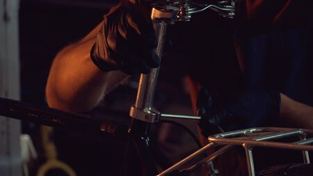 theme small business bike repair. A young Caucasian brunette man wearing safety goggles, gloves and...