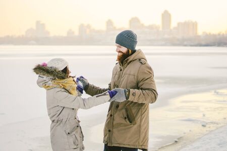 Young couple cheerfully flounders in snow. Between comic fight. Happy young couple hugs in winter snowy woods. Romantic lifestyle men and women in love.の写真素材