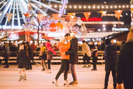 Beautiful couple have fun in ice arena. active date ice skating on ice arena in evening city square in winter Christmas Eve. St. Valentine's Day at the city ice rink. New Year's holidays in city Kiev.の写真素材