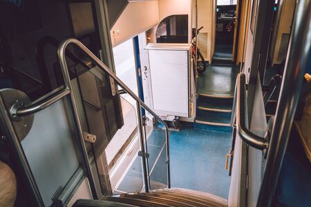 Interior of railway passenger car of the second class in train in Lombardy in Italy. Train interior. Blue seats in a commuter train. Interior of an Italian railway carriage. Empty without people.の写真素材