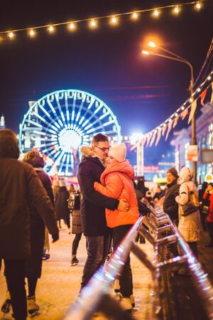 Beautiful Couple Ice Skating In City Centre. Young couple skating at a public ice skating rink outdoors. Theme ice skating rink and loving couple. Amazing winter holiday. Saint Valentines Day.の写真素材