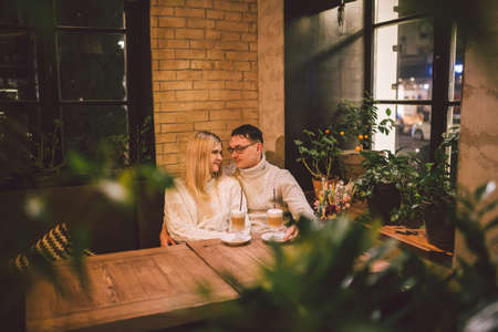 Happy Couple Meeting And Drinking Coffee. love and romantic date in downtown cafe restaurant. Young happy couple in love in cafe. Young couple date in cafe, talking and kissing at Christmas time.の写真素材