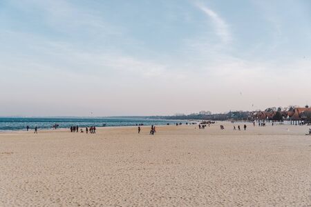 People walk on sandy beach in winter. Perfect winter vacation. People chill out in cold season on...