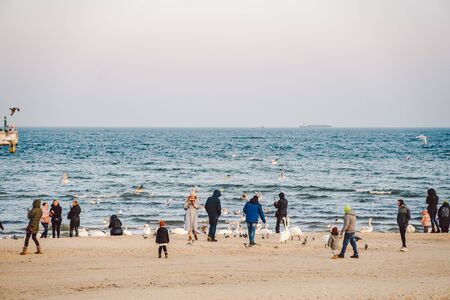 Poland, Sopot, February 9, 2020. People at beach in Sopot. Crowd on Beach During Winter. enjoying day in sunny winter near sea. People walking along on Baltic sea, surf line on warm sunny winter day.のeditorial素材