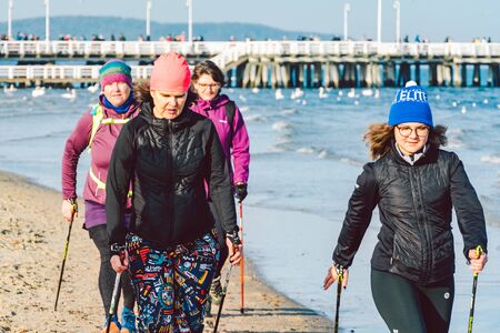 People walk on sandy beach in winter. Perfect winter vacation. People chill out in cold season on coast. Gdansk, Poland February 9, 2020. Walking crowd of people in city Sopot along beach Baltic Sea.のeditorial素材