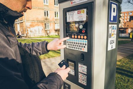 Payment for parking in the City of Gdansk, Poland on February 8, 2020. A person uses monobank credit card for nfc payment in parking terminal. Paid Automatic payment for parking places in city.のeditorial素材