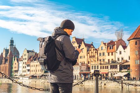 Theme of tourism in Poland. Traveling in Gdansk. A male traveler uses a phone on the embankment of...