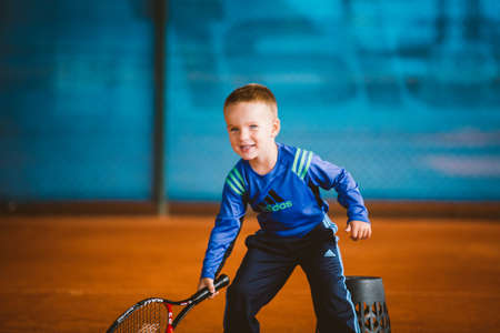 Child playing tennis on outdoor court. September 20, 2016. Ukraine, Kiev. Little tennis great player. Children sportswear adidas. Child athlete Ambassador Adidas.のeditorial素材