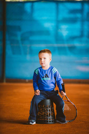 Child playing tennis on outdoor court. September 20, 2016. Ukraine, Kiev. Little tennis great player. Children sportswear adidas. Child athlete Ambassador Adidas.のeditorial素材