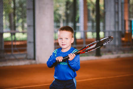 Child playing tennis on outdoor court. September 20, 2016. Ukraine, Kiev. Little tennis great player. Children sportswear adidas. Child athlete Ambassador Adidas.のeditorial素材