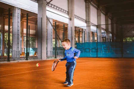 Child playing tennis on outdoor court. September 20, 2016. Ukraine, Kiev. Little tennis great player. Children sportswear adidas. Child athlete Ambassador Adidas.のeditorial素材