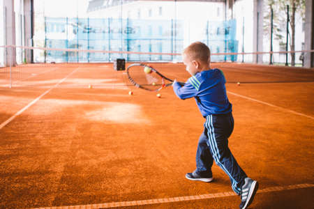 Child playing tennis on outdoor court. September 20, 2016. Ukraine, Kiev. Little tennis great player. Children sportswear adidas. Child athlete Ambassador Adidas.のeditorial素材