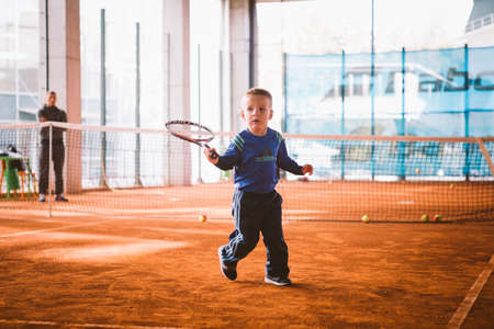 Child playing tennis on outdoor court. September 20, 2016. Ukraine, Kiev. Little tennis great player. Children sportswear adidas. Child athlete Ambassador Adidas.のeditorial素材