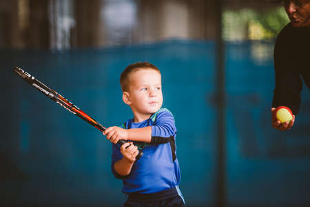 Child playing tennis on outdoor court. September 20, 2016. Ukraine, Kiev. Little tennis great player. Children sportswear adidas. Child athlete Ambassador Adidas.のeditorial素材