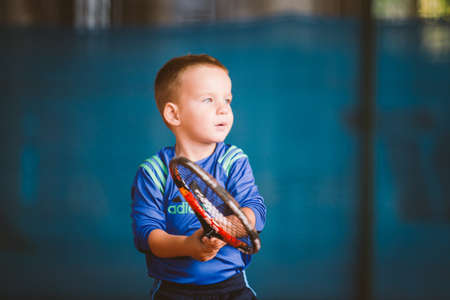 Child playing tennis on outdoor court. September 20, 2016. Ukraine, Kiev. Little tennis great player. Children sportswear adidas. Child athlete Ambassador Adidas.のeditorial素材