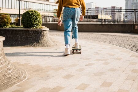 Young handsome woman riding on a skateboard. Portrait of sport female model in urban style....