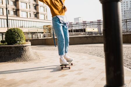 Skateboarding at city. Female, enjoyment. Hipster girl riding skate board. Ride, style. Extreme sport and emotions concept. Alternative lifestyle. Woman skateboarder skateboarding at city.の写真素材