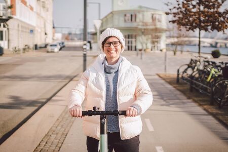 Young woman riding an electric scooter on bike path in copenhagen, modern girl, new generation,...