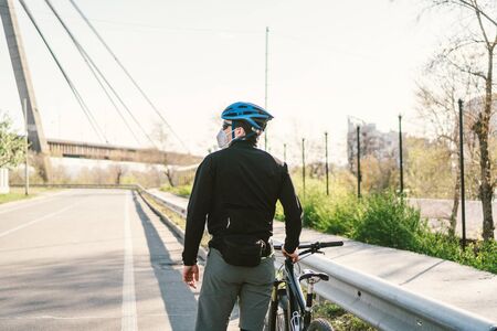 Male cyclist wearing respirator face mask with heavy duty protective filter. Man on bike wearing respirator face mask with heavy duty protective filter. Safety breathing masks. Pollution concept.の写真素材