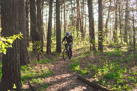 Young man in protective mask from environmental pollution riding mountain bike on cross country...