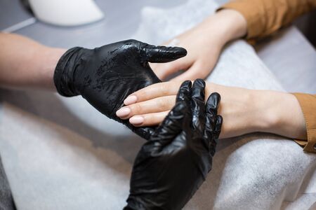 Close-up of a manicurist doing moisturizing and hand massage for a client. The theme is skin care and body beauty. Spa and Manicure concept. Soft skin. Cosmetology, applying.の写真素材