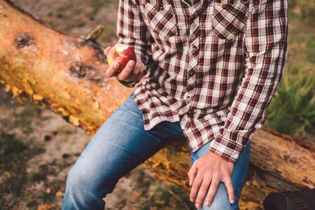 man eating an apple on hiking trip in forest. Hiker taking break while trekking in wilderness. male...
