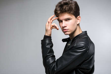 Young fashion man passing his hand through his hair. Male fashion model with hand in hair. Man Hair...