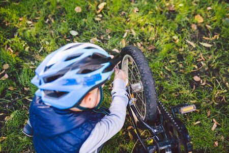Active leisure for children in the park. A child is studying the mechanism of a mountain bike....