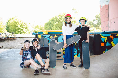 Group of children friends enjoying day at skate park. Youth, togetherness and friendship concept. Group of kids skateboarders. Urban little ones skaters girls and boy in skate park.の写真素材