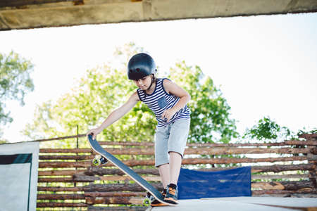 Skater boy rides on skateboard at skate park ramp. Kid practising skateboarding outdoors on skatepark. Youth culture of leisure and sports. Skateboarder doing trick on skateboard on halfpipe ramp.の写真素材