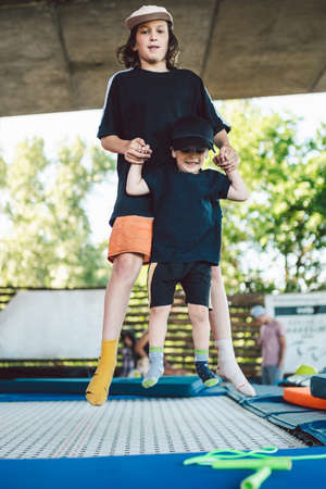 Two little boys jumping on trampoline in sport center. Kids having fun together. Active leisure....