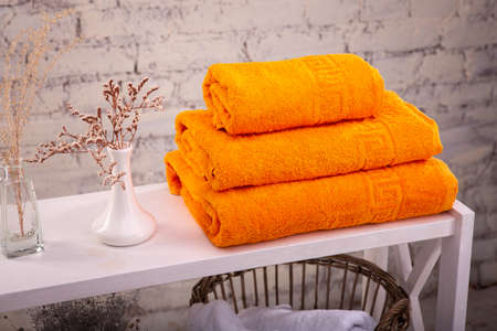 Rack with a stack of three color towels and baskets with clean white towels and toilet decor near a...
