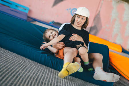Two happy emotions children, brothers playing and having fun while jumping on bouncing trampoline in...