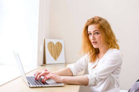 Beautiful young woman using laptop in office, typing, learning, watching webinars, video call, client consultations, distant work. Freelance and management. E commerce, education, Internet technology.の写真素材