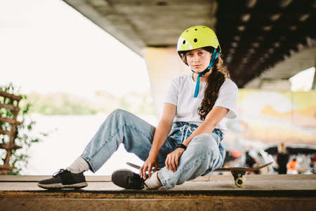 Portrait confident, cool young female skateboarder at outdoor skate park. Urban girl with skate...