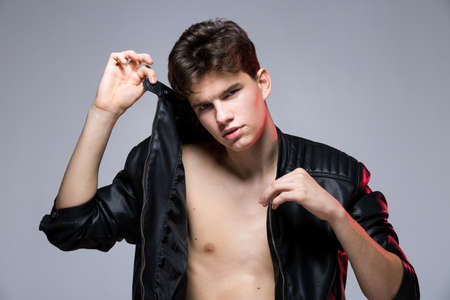 Fashionable Handsome young man in leather jacket posing in the studio against the background of the...